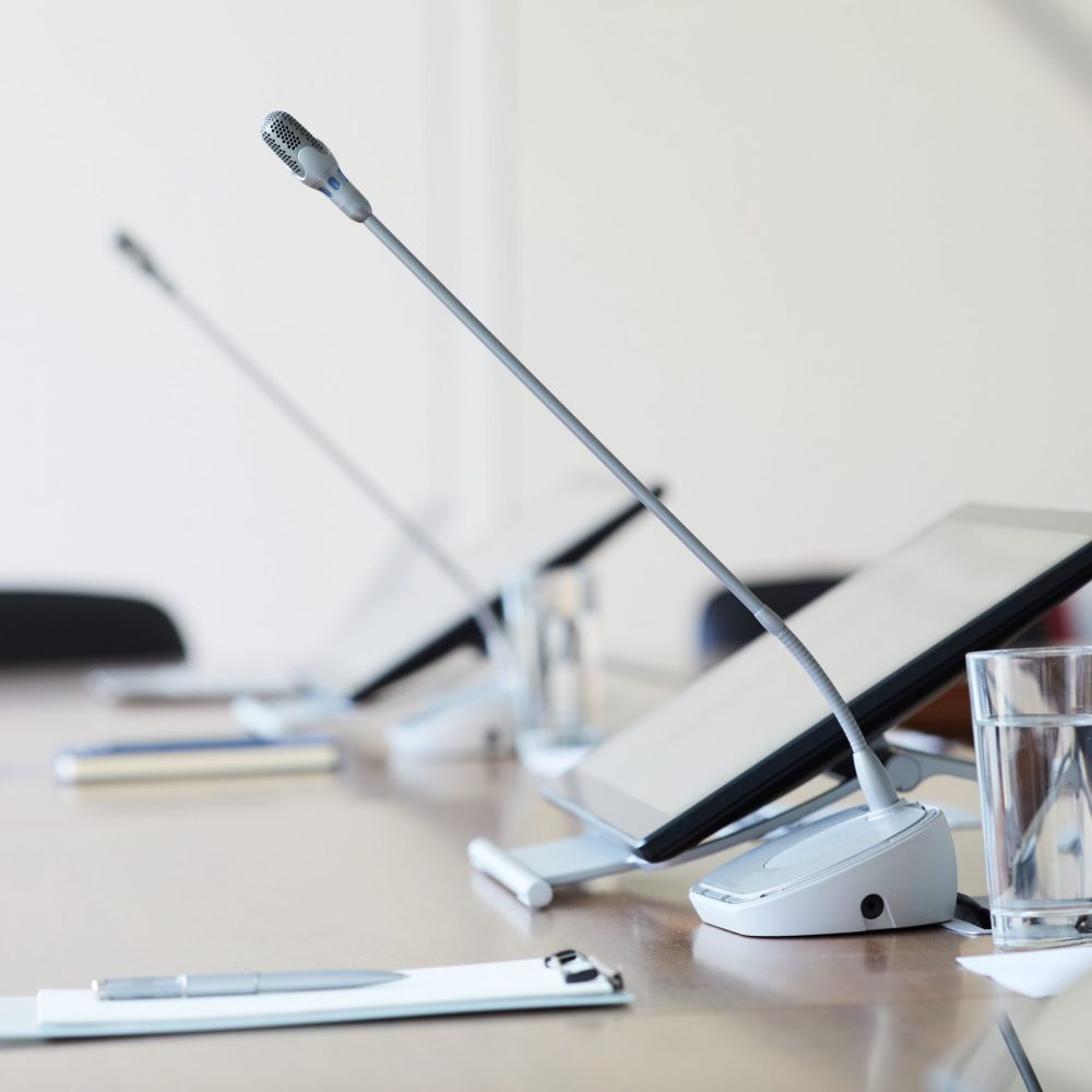 Image of empty table with computer and microphone at conference room