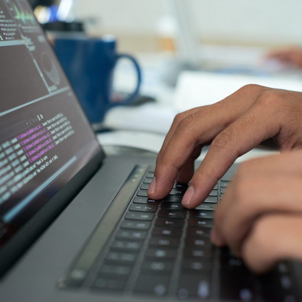 Hands of programmer writing code on laptop